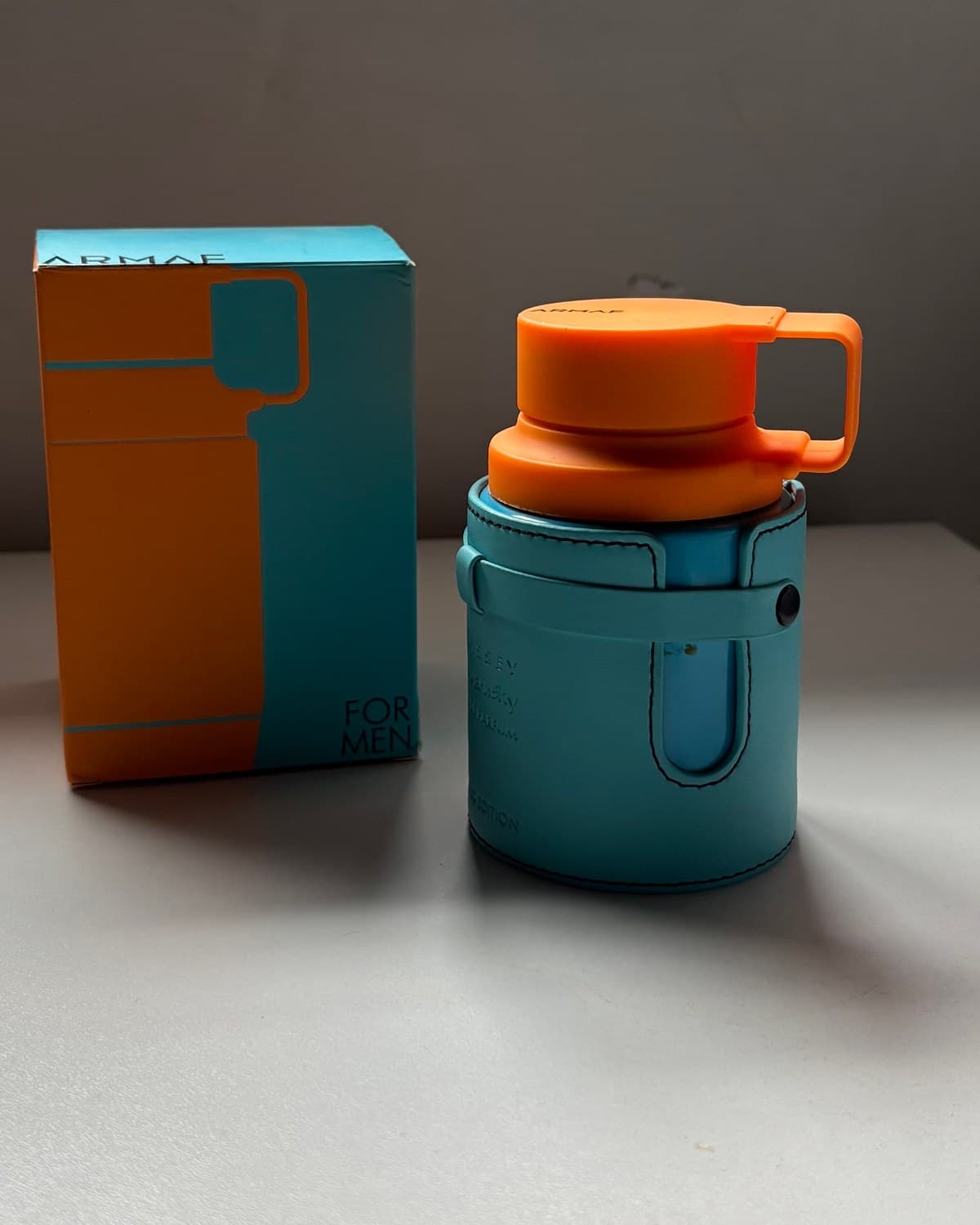 Armaf Odyssey Mandaryn Sky, frasco de 100 ml, sobre la mesa